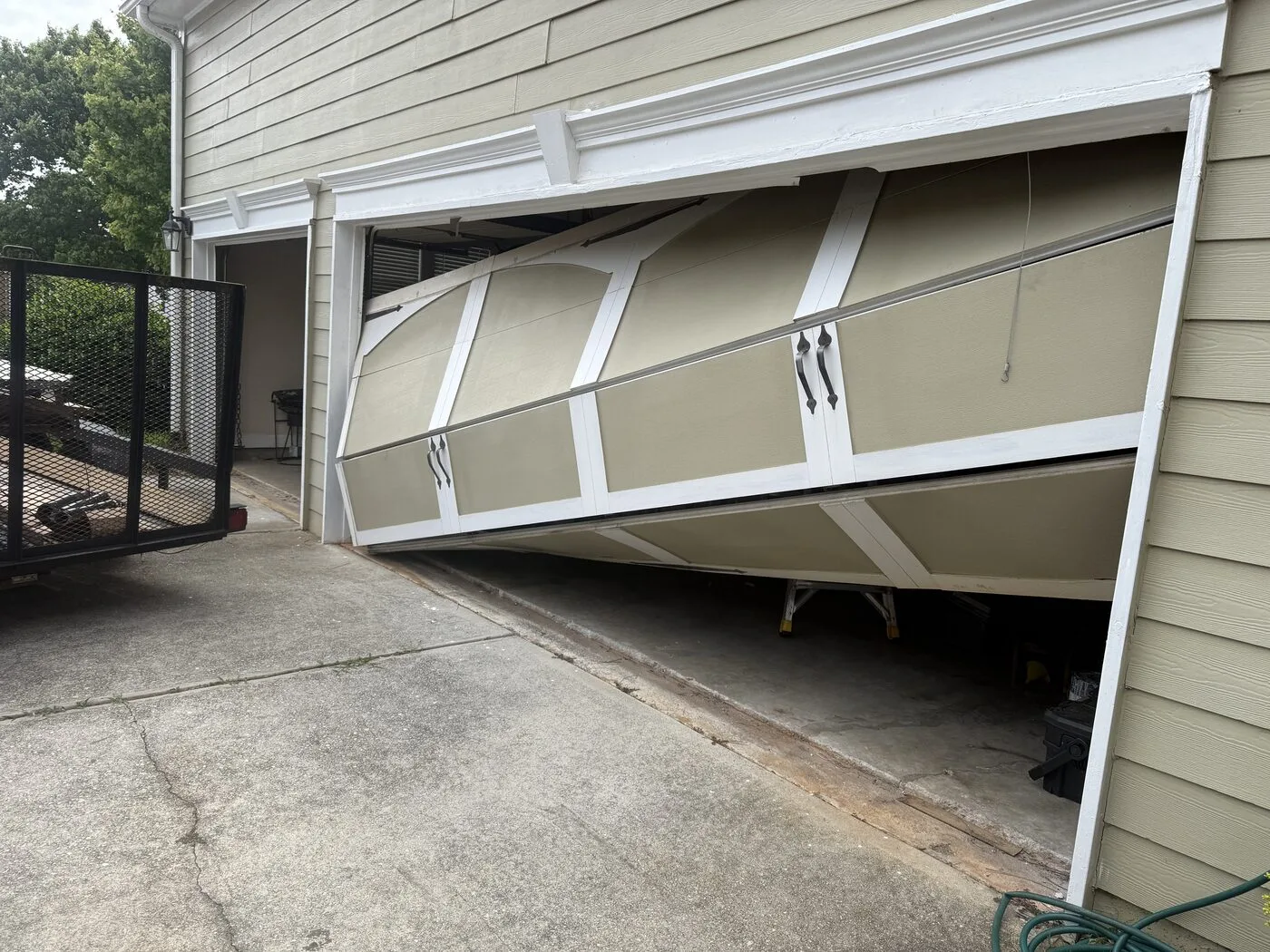 Garage door hanging diagonally out of its tracks, stuck half open, Peachtree Corners GA