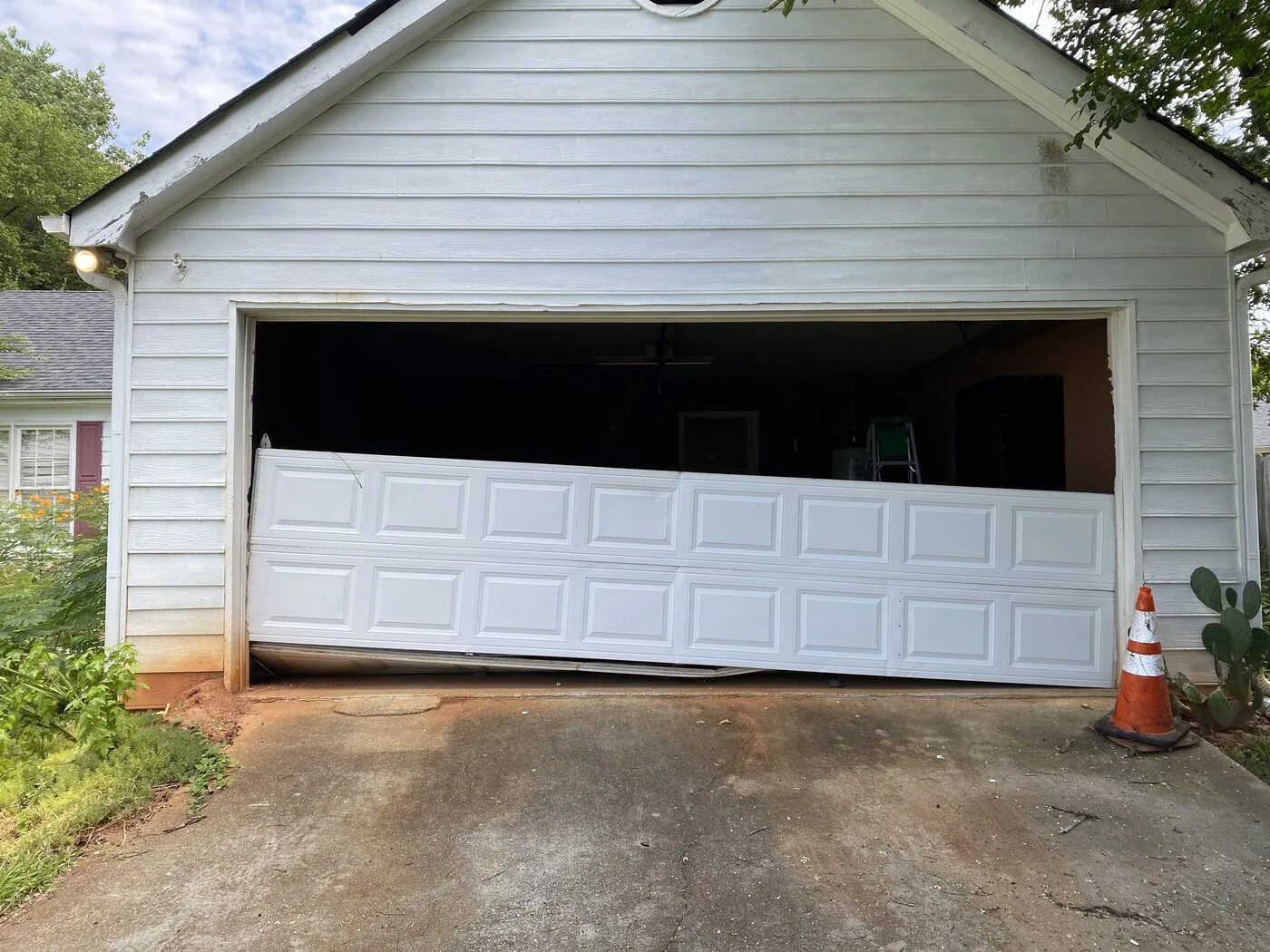 Garage door with two panels damaged by vehicle impact, Dunwoody GA
