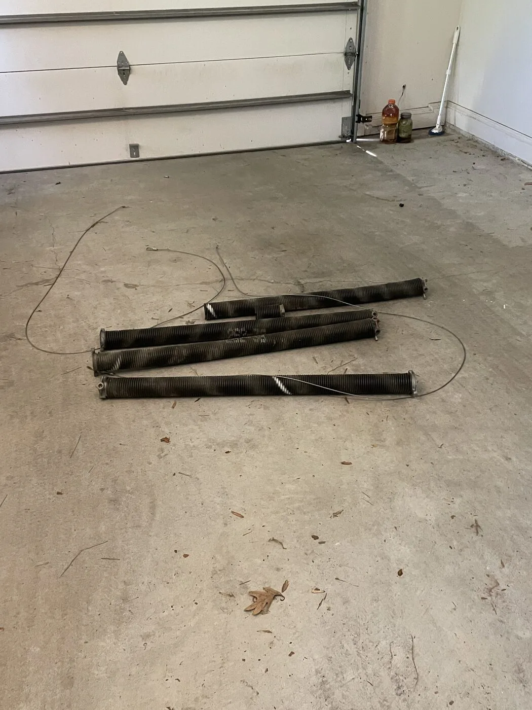 Four old torsion springs removed and laid on the garage floor, Suwanee GA