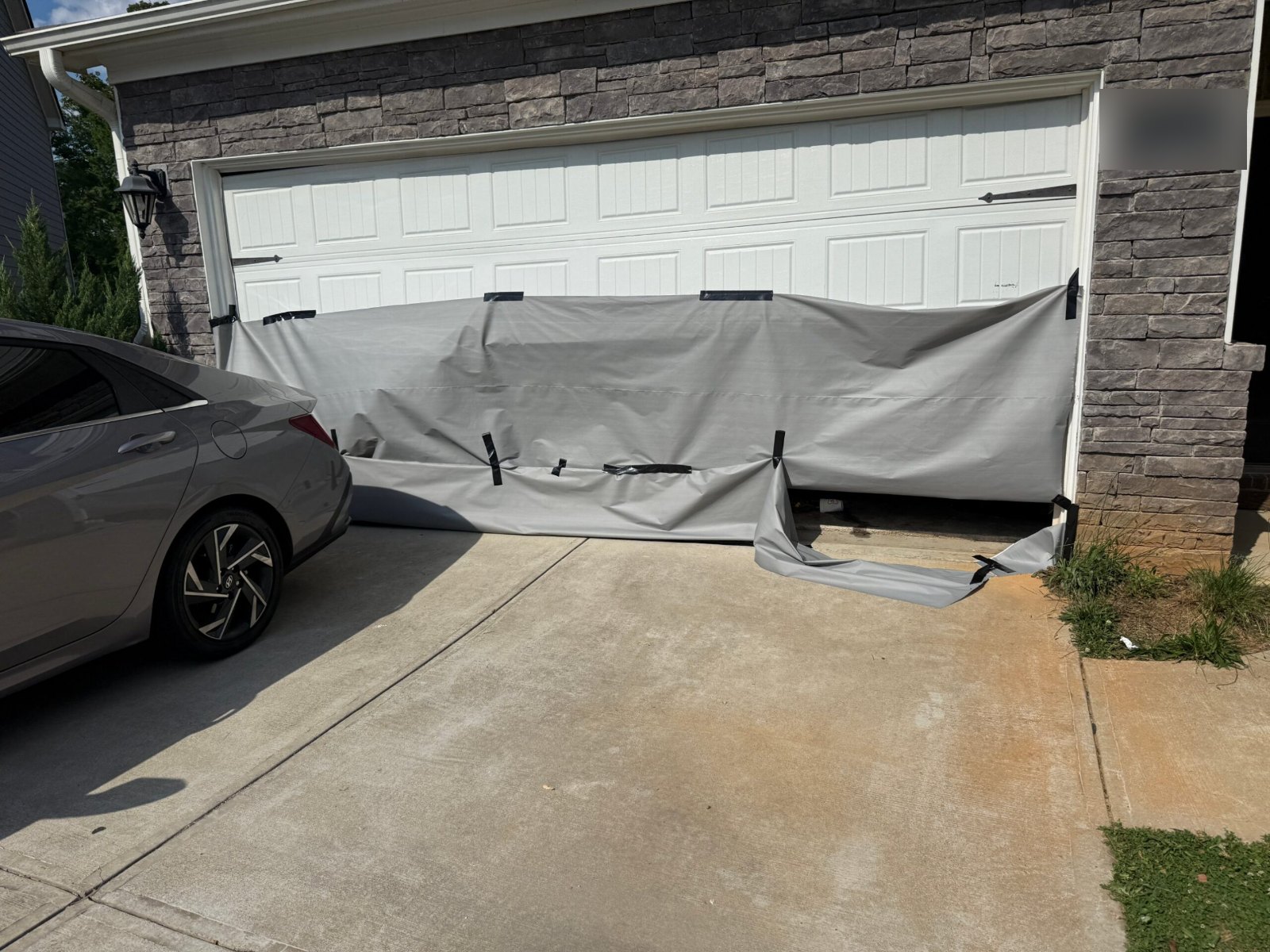 Double garage door crushed by a car and covered with a tarp in Stone Mountain, GA, before replacement