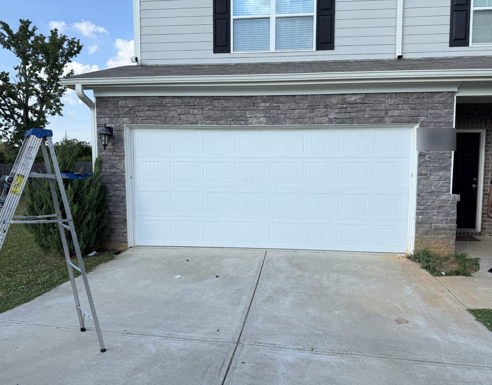 New white double garage door installed after car damage on a stone-front home in Stone Mountain, GA
